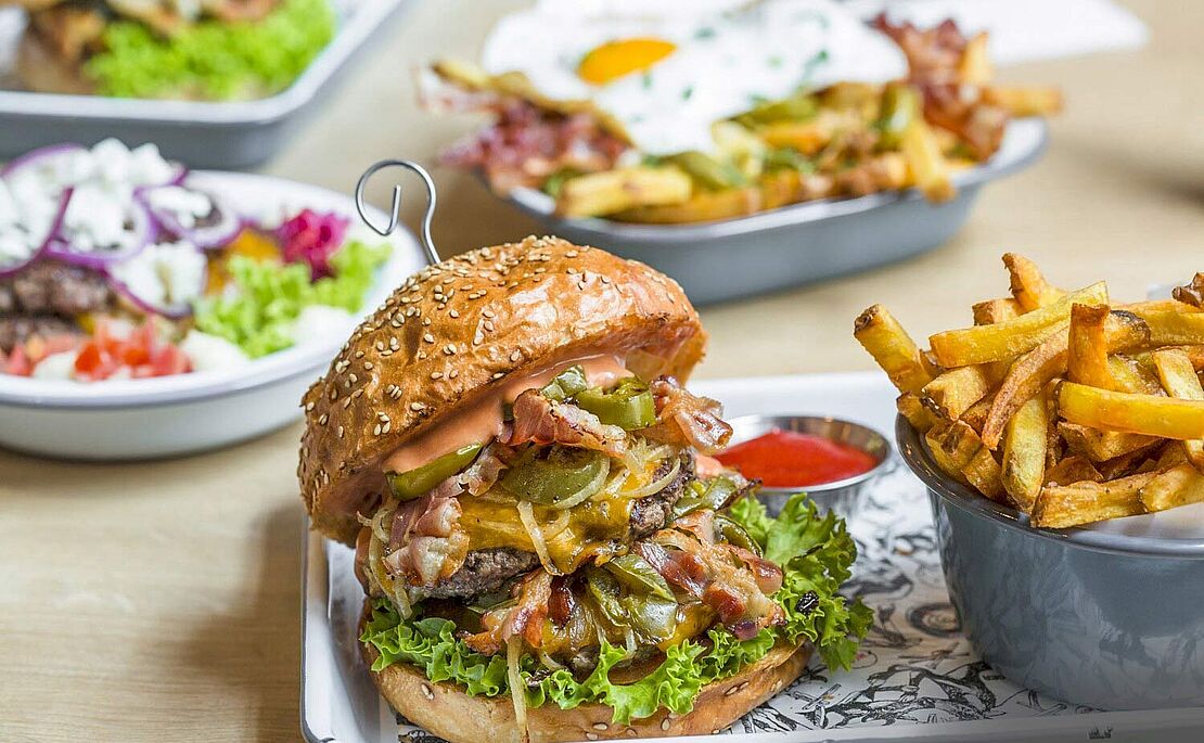 Teller mit einem Burger und einer Schale mit Pommes Frites vom Lokal Omnom