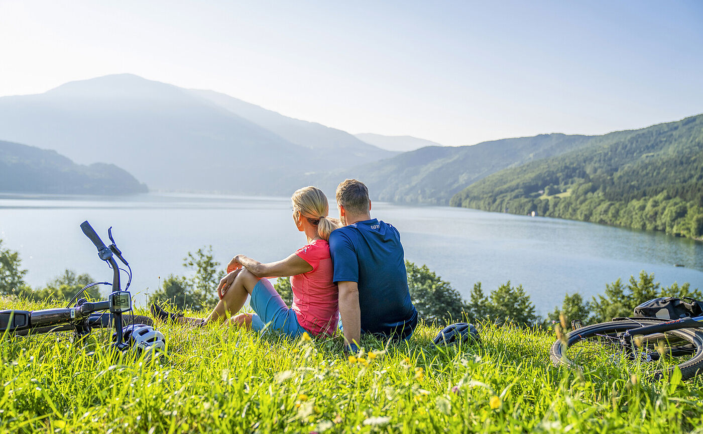 Frau und Mann sitzen am Ufer des Millstätter Sees