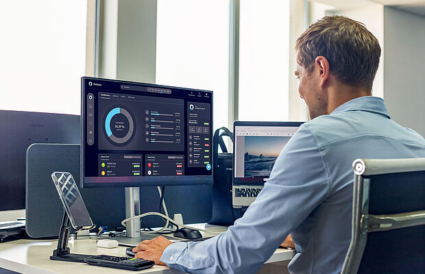 Mann von seitlich hinten, der vor seinem PC sitzt