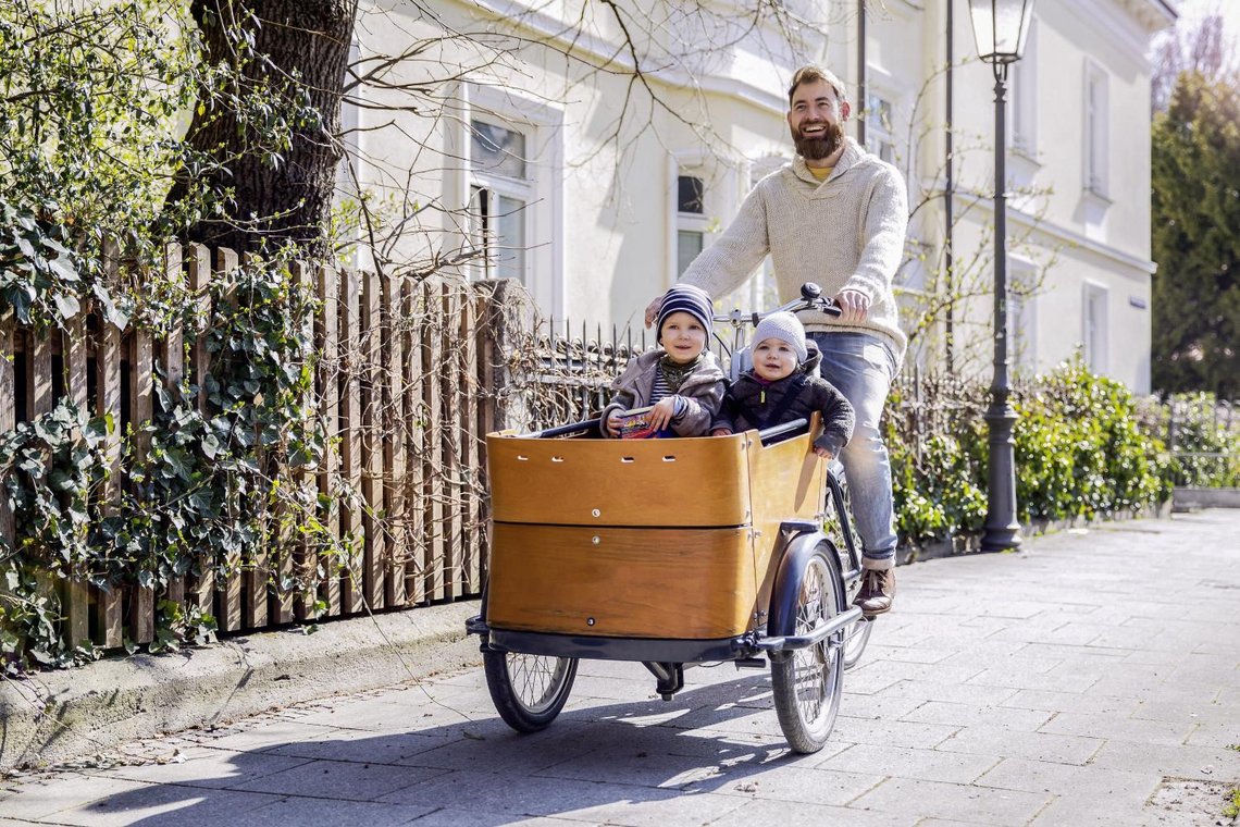 Lastenrad mit Mann und zwei Kindern