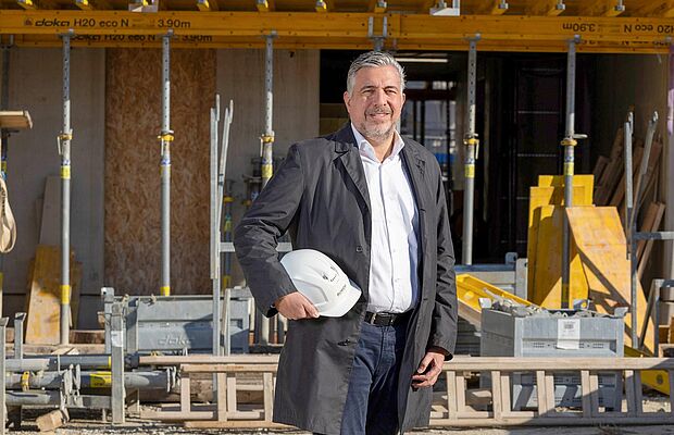 Andreas Holler mit Bauhelm in der Hand auf einer Baustelle