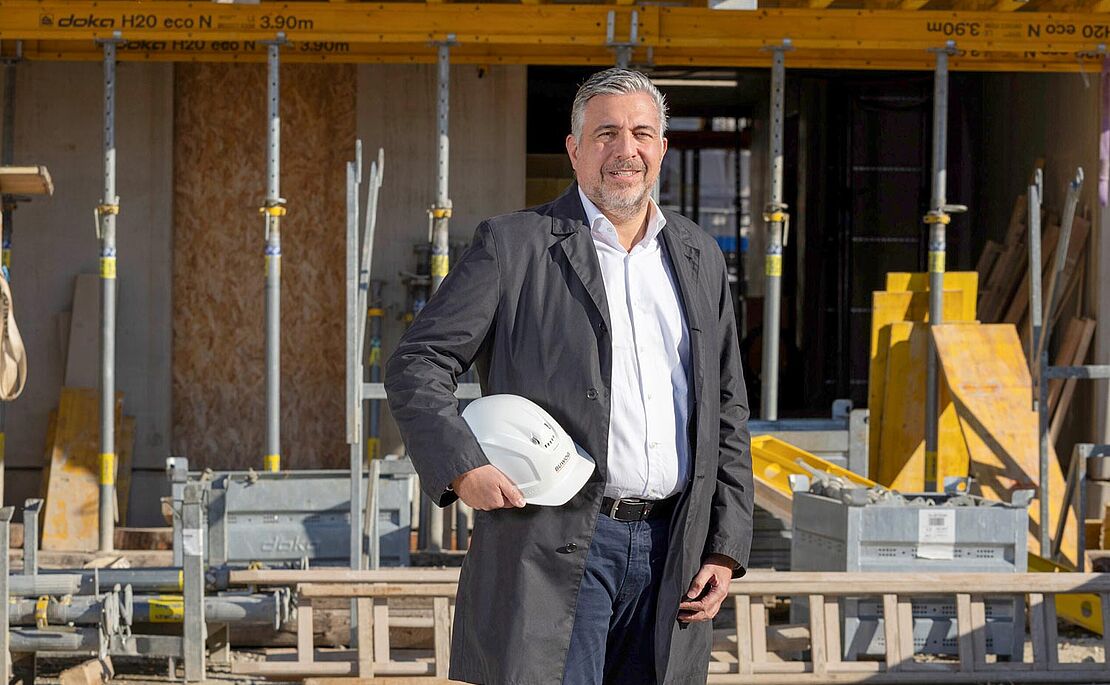 Andreas Holler mit Bauhelm in der Hand auf einer Baustelle