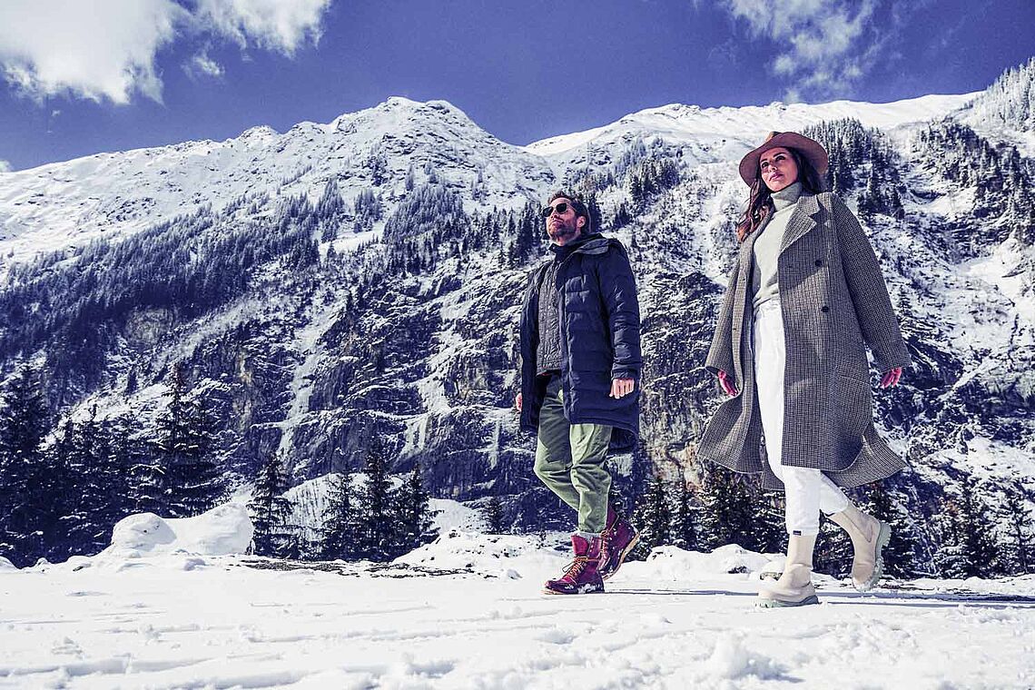 Mann und Frau spazieren in der verschneiten Winterlandschaft in Bad Gastein