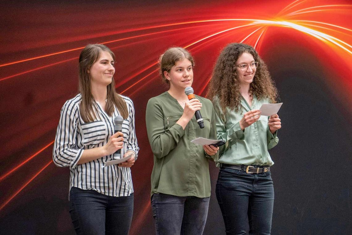 Foto der drei Mädchen auf einer Bühne mit Mikrofon in der Hand