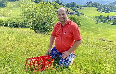 Stefan Edtbauer auf einer Wiese knieend, davor sein Roundgrip-Metallreifen in rot