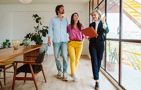 Junges Paar mit Maklerin bei einer Wohnungsbesichtigung