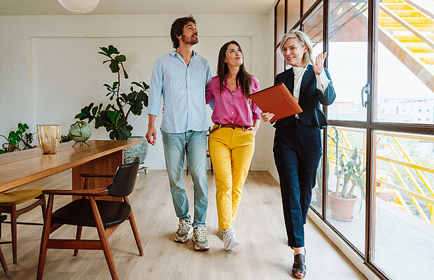 Junges Paar mit Maklerin bei einer Wohnungsbesichtigung