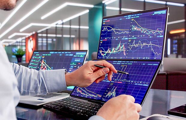 Hände mit einem Stift in der Hand, die auf einem Display mit vielen Grafiken tippen