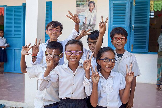 Gruppe von sechs Schulkindern, alle mit Brille, alle machen das Victoryzeichen