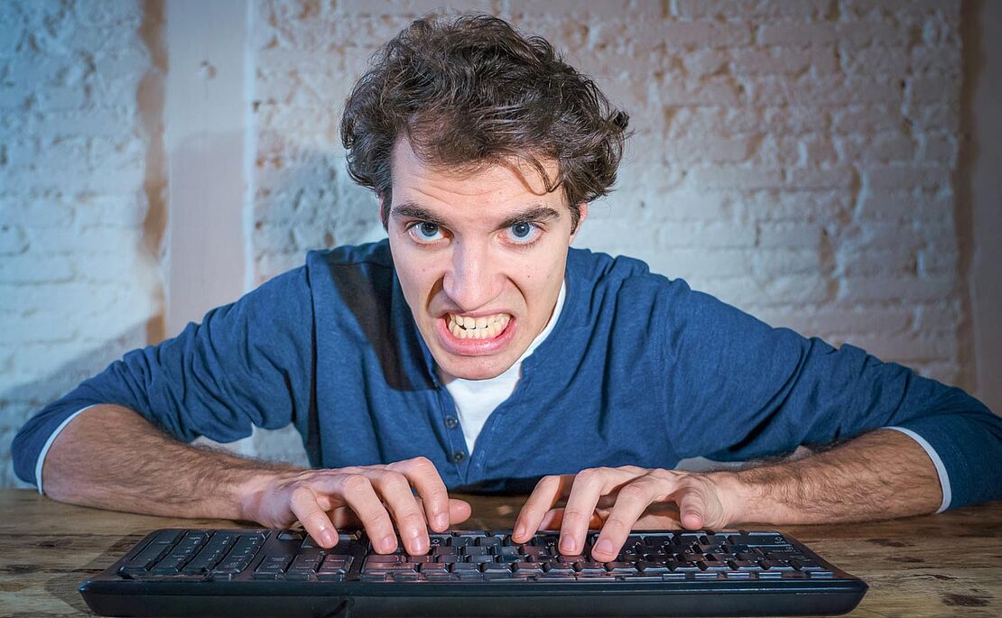 Mann mit knirschenden Zähnen vor dem Computer