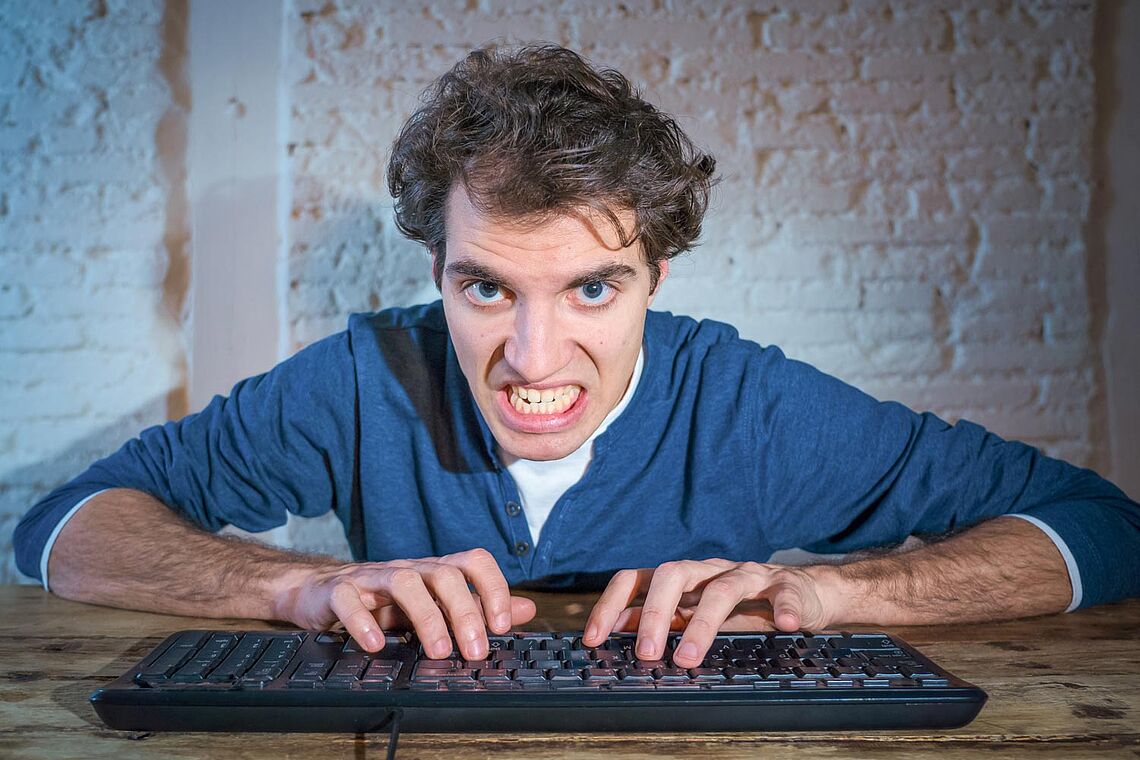 Mann mit zusammen gebissenen Zähnen am Computer