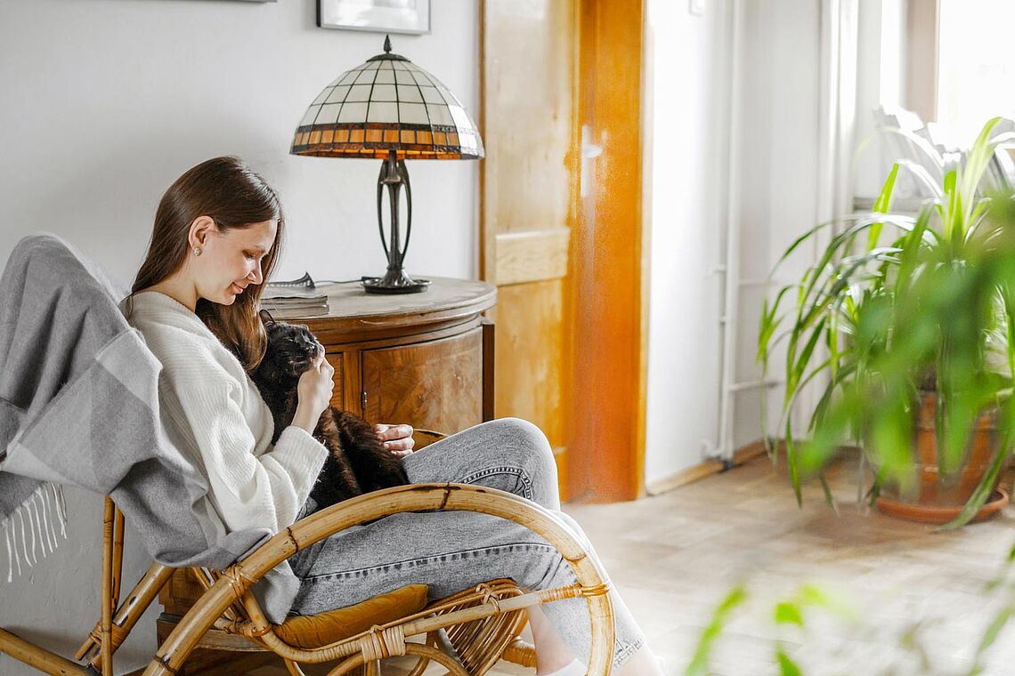 Frau kuschelt auf Sofasessel mit Hund