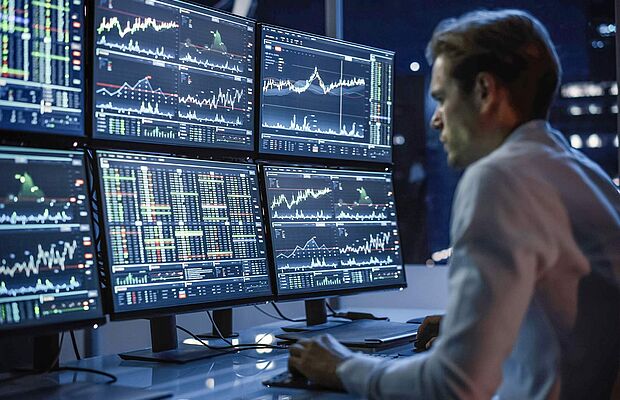Mann vor 6 Bildschirmen mit diversen Charts