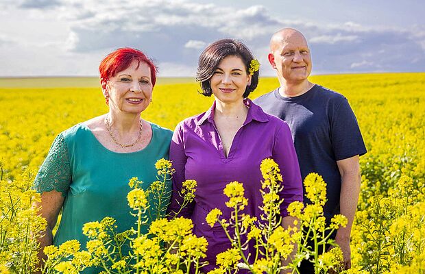Liselotte Puta und Katrin und Stephan Segel in einem gelb blühenden Feld