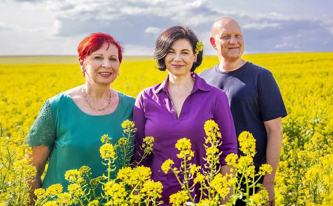 Liselotte Puta und Katrin und Stephan Segel in einem gelb blühenden Feld