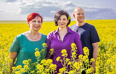 Liselotte Puta und Katrin und Stephan Segel in einem gelb blühenden Feld